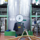 Interno di un impianto industriale per la conservazione dell'olio extravergine di oliva, con grandi serbatoi in acciaio inox, manometri, tubazioni e strutture metalliche per il controllo della qualità e dello stoccaggio del prodotto.